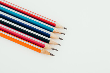 Multicolored wooden graphite pencils on light background. Top view.