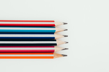 Multicolored wooden graphite pencils on light background. Top view.