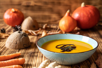 orange Suppe aus Kürbissen vom Hokkaido in einer Schale auf einem braunem Tisch aus Holz im Herbst...