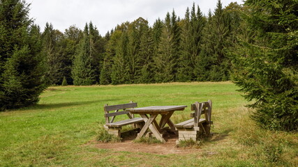 Fototapeta na wymiar Wooden bench and table rest place at a mountain meadow in Sumava National Park