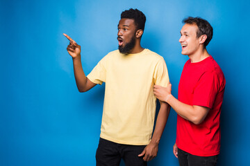 Two mixed race men pointed side isolated on blue background - obrazy, fototapety, plakaty