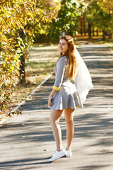 A young girl in sports clothes walks through the park and smiles in sunny weather
