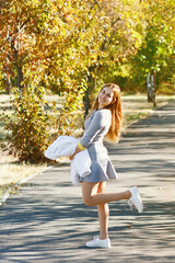 A young girl in sports clothes walks through the park and smiles in sunny weather
