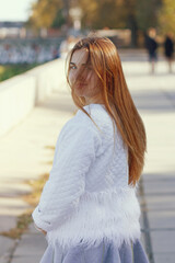Portrait of gorgeous happy girl in grey dress and white jacket at sunset time.
