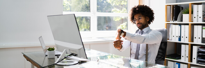Black Man Stretching At Office Desk