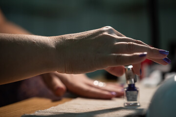 The woman is painting her nails purple, close up