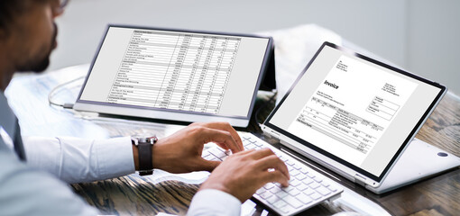 Looking At Invoice And Spreadsheet On Laptop