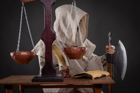 Halloween concept. The executioner of the holy inquisition with an ax weighing other people's sins