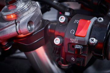 Close-up of the start button of a sports motorcycle and steering grip with the rest of the functions