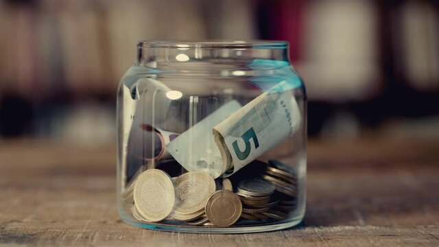 Hand putting Coins in glass jar