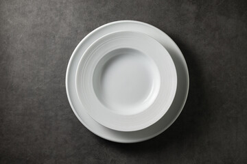 two beautiful modern plates on a dark gray concrete background, top view 