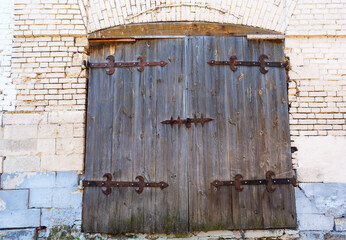 Old wooden gate with forged metal hinges