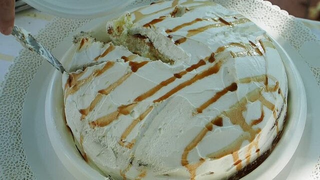 Lunch at home with the family. A piece of cake made with cream, caramel and sponge cake is cut with a knife.