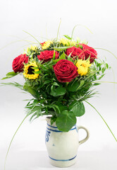 bouquet of roses an sunflowers in a vintage pitcher