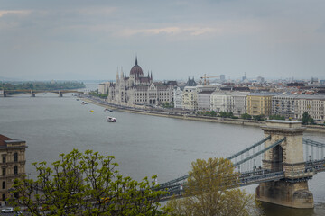 Fototapeta premium Budapest city landscape with the famous Chain bridge over the Danube river and the Parliament building in the background on a cloudy day, Hungary