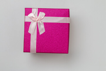 isolated small purple present box with a pink bow, closed bright holiday gift box with a pink lace bow on top lying on a white background