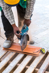 Construction work on pavement. Installation of concrete paver blocks on the sidewalk. A worker makes measurements, mark and cut build materials by a disc cutter.