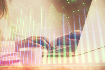 Double exposure of woman hands working on computer and forex graph hologram drawing. Financial analysis concept.