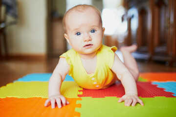 Smiling baby girl lying on play mat