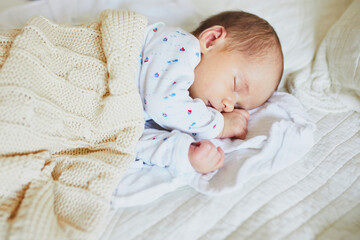 1 month old baby girl sleeping under knitted blanket