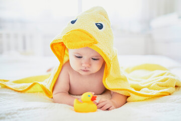 Cute little girl playing with rubber duck after having bath