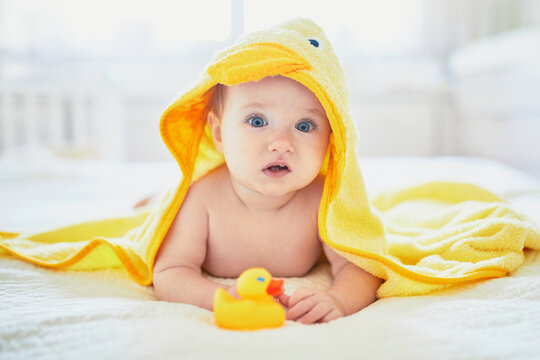 Cute little girl playing with rubber duck after having bath