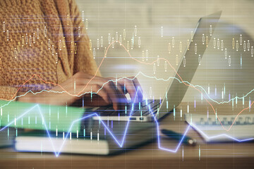 Double exposure of woman hands typing on computer and forex chart hologram drawing. Stock market analysis concept.