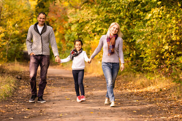 Naklejka na ściany i meble happy family walking in the autumn park