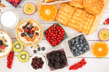Breakfast Served in the morning with Butter bread and corn flakes Whole grains and raisins with milk in cups and Strawberry, Blueberry, Raspberry, Kiwi, Fresh Orange  on the breakfast table.
