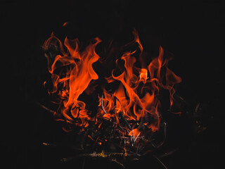 Close-up of bright red orange fire flames on dark background. Night bonfire.Dangerous woodfire. Beautiful spurts of flame abstract background.