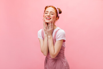 Positive lady with gentle make-up dressed in pink dress laughs on isolated background
