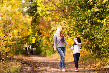 Obraz premium happy family: mother and child little daughter play cuddling on autumn walk in nature outdoors