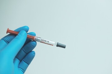 Obraz premium Doctor hand with blue gloves and Covid-19 vaccine