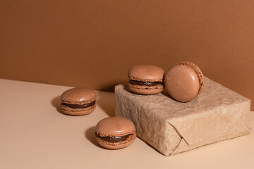 Brown chocolate macaroons on paper gift box on beige background. Sweet food. Tasty desert. Homemade meal.