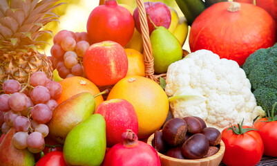 Group vegetables and Fruits Apples, grapes, oranges, pineapples, bananas in a wooden basket with carrots, tomatoes, guava, chili, eggplant, golden pod, green salad on wooden table in nature background