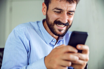 Obraz na płótnie Canvas Closeup of attractive smiling bearded businessman holding smart phone.