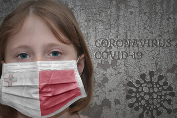 Little girl in medical mask with flag of malta stands near the old vintage wall with text coronavirus, covid, and virus picture. Stop virus concept