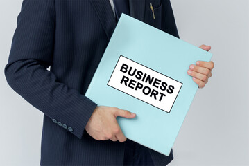 A businessman holds a folder with documents, the text on the folder is - BUSINESS REPORT