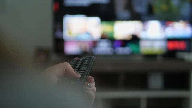 Person choosing movie on netflix in the living room of his house