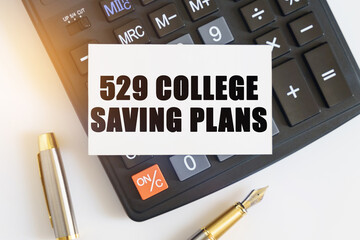 On the table there is a pen, a calculator and a business card on which the text is written - 529 COLLEGE SAVING PLANS