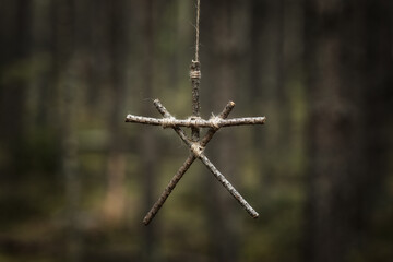 Witchcraft sticks symbol. Magic occult symbol. Totem hanging on tree in dark forest. Halloween concept.