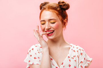 Green-eyed girl smiles sweetly against pink background. Portrait of redhead woman with yellow eye shadows