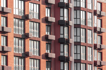 Many floors. Facade of a new house. Geometry in architecture. Residential real estate market. Rhythm in photography. Apartments in the city. Construction of houses. Identical windows to the floor.