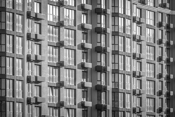 Many floors. Facade of a new house. Geometry in architecture. Residential real estate market. Rhythm in photography. Apartments in the city. Construction of houses. Identical windows to the floor.