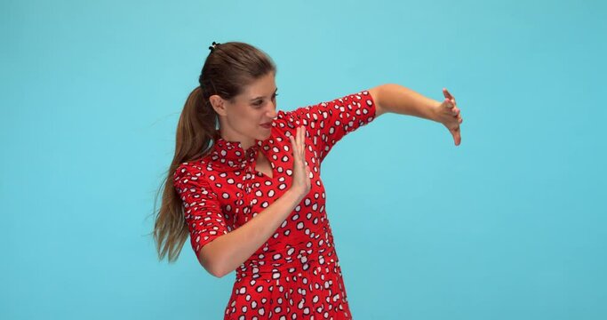 Studio, slow motion, young woman in a red dress fights against the wind