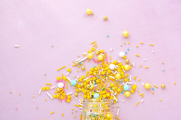 Yellow sugar sprinkles grainy on pink background, close-up flat lay