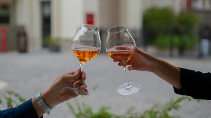 young couple toasting with glasses of rosé wine at the table outside the restaurant.