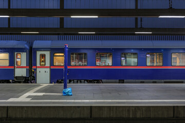Side view of blue passenger train at empty platform railway station in Düsseldorf, Germany.
