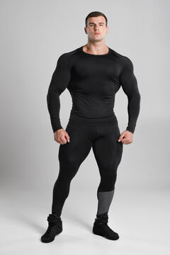 Muscular man in black compression sportswear on gray background