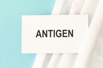 Word antigen with medical mask on a blue background.
